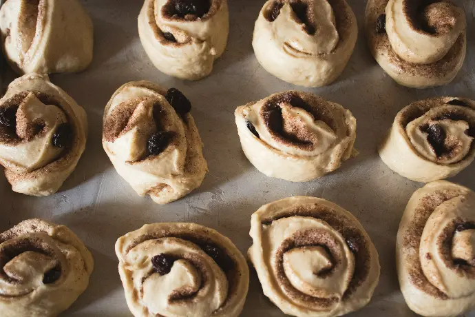 a baking sheet filled with cinnamon rolls on top of a table